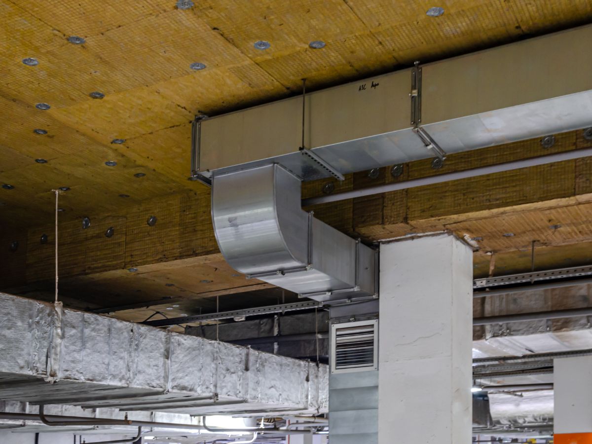 View of an empty building's ceiling showcasing visible pipes and ducts in an industrial design.